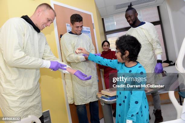 New England Revolution's Cody Cropper, Joshua Smith, and Kei Kamara get stamps from Vai at Boston Children's Hospital on March 8, 2017 in Boston,...