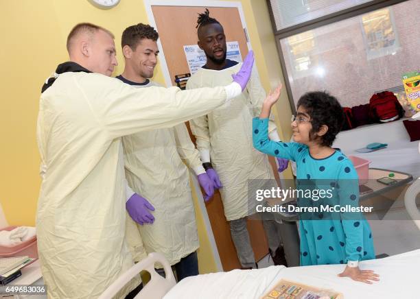 New England Revolution's Cody Cropper, Joshua Smith, and Kei Kamara slap high fives with Vai at Boston Children's Hospital on March 8, 2017 in...