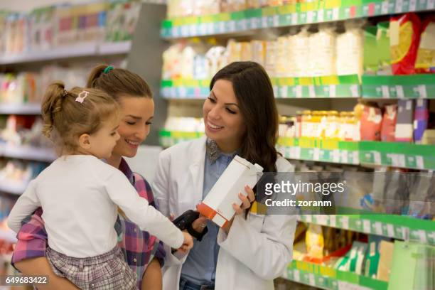 verkäuferin mit mutter und tochter - mom buying milk stock-fotos und bilder