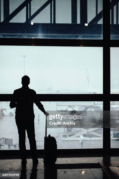 silhouette of man looking through the window at the airport - vip room stock pictures, royalty-free photos & images