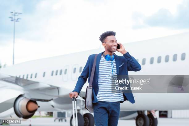 jonge zakenman praten over slimme telefoon vóór vliegtuig - man airport stockfoto's en -beelden