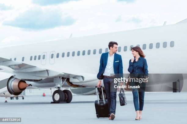 business colleagues walking on tramac in front of airplane. - businesswoman airport stock pictures, royalty-free photos & images
