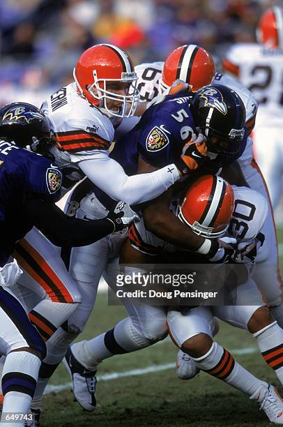 Anthony Davis of the Baltimore Ravensgets pulled down by Jamel White and Darrin Chaverini of the Cleveland Browns during the game at the PSINET...