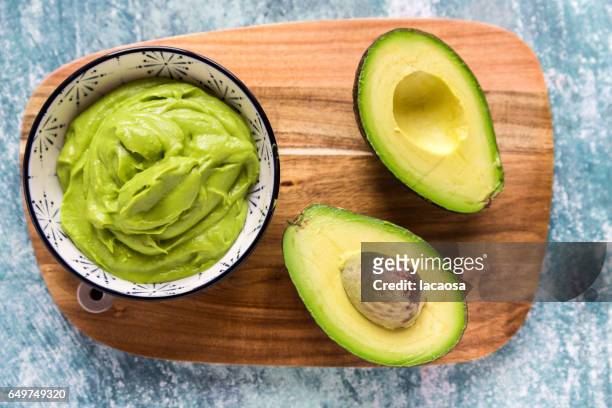 bowl of guacamole and sliced avocado - avocado fotografías e imágenes de stock