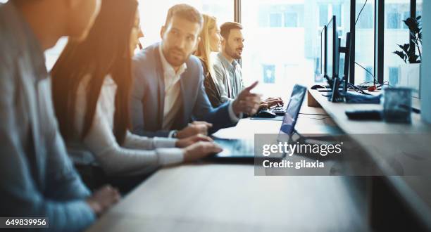 expertos trabajando en una computadora. - multitareas fotografías e imágenes de stock