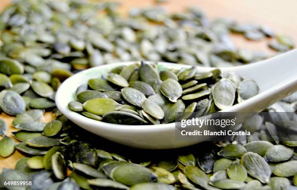 pumpkin seeds on a spoon - pumpkin seed stock pictures, royalty-free photos & images