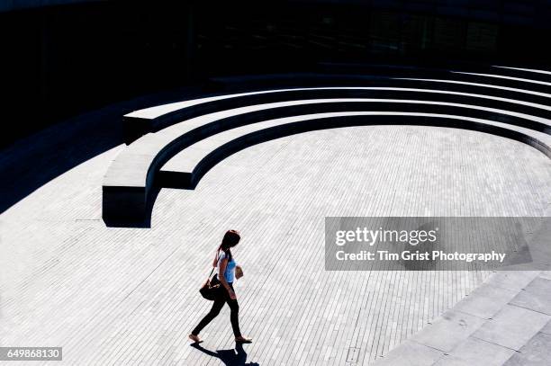 young woman walking through the scoop, london, uk - forte contrasto foto e immagini stock