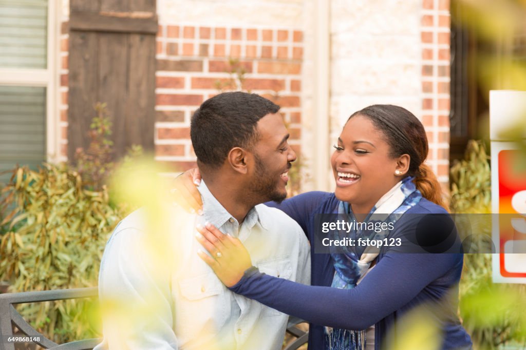 Excited couple in front of first home real estate purchase.