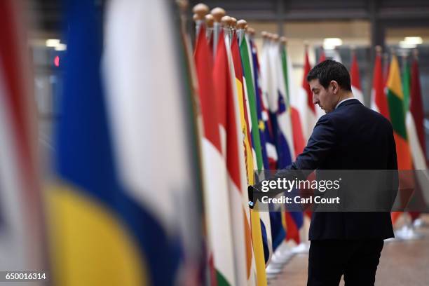 Member of staff adjusts flags in the arrival area of the Europa building at the Council of the European Union on the first day of an EU summit, on...