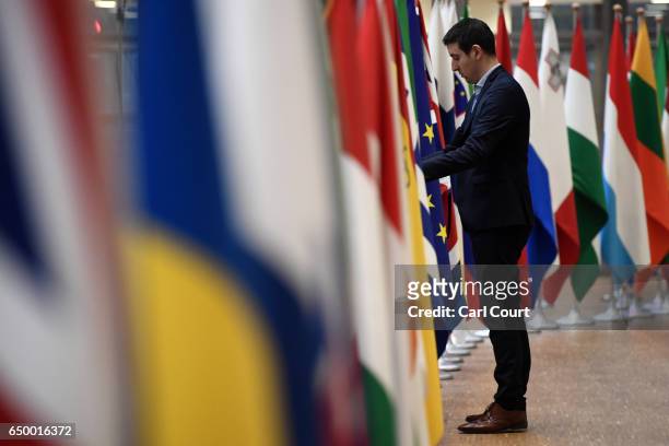 Member of staff adjusts flags in the arrival area of the Europa building at the Council of the European Union on the first day of an EU summit, on...