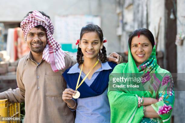 indian parents with daughter holding medal - rural scene stock pictures, royalty-free photos & images