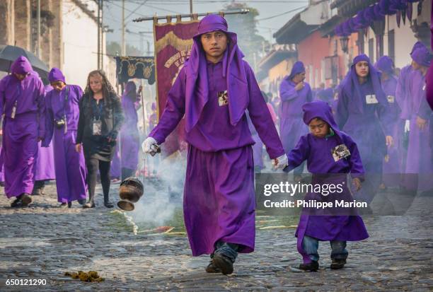 sombre father and son in traditional clothing burning incense during holy week in antigua, guatemala - holy week banner stock pictures, royalty-free photos & images