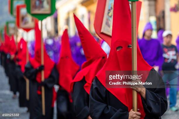 penitents wearing hoods in procession during holy week (semana santa) - antigua guatemala - holy week banner stock pictures, royalty-free photos & images