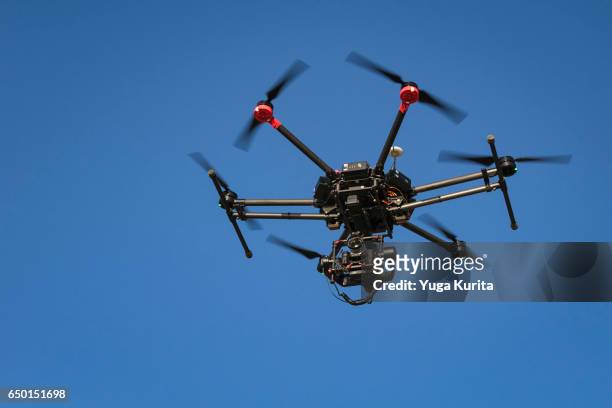 professional drone hovering against the blue sky - flying drone stock-fotos und bilder