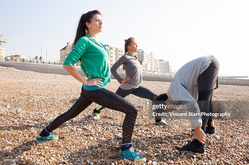 Man and women warm up training, stretching on Brighton beach