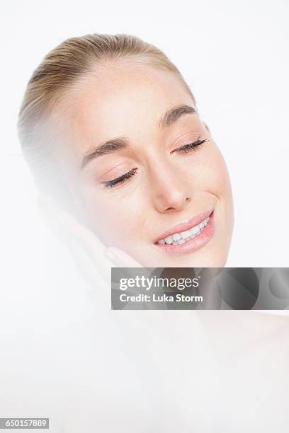 bare shouldered woman with hands to face eyes closed smiling - lens flare white background stock pictures, royalty-free photos & images