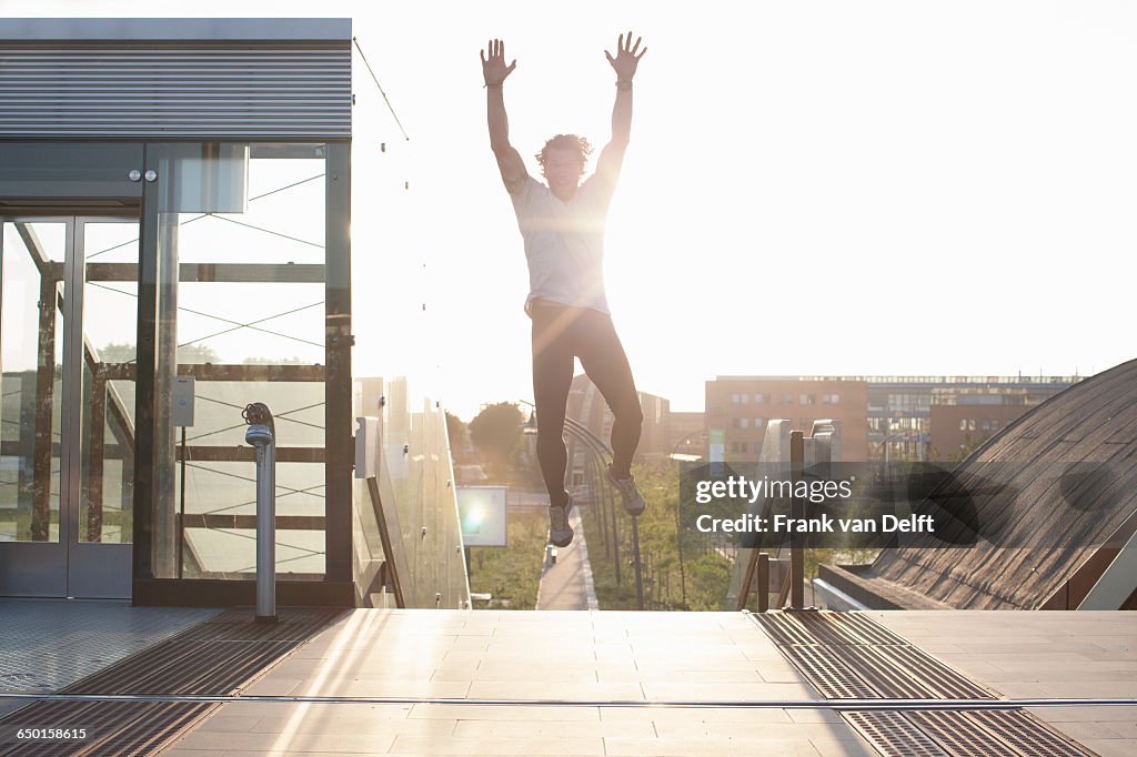 Man training, jumping mid air on footbridge