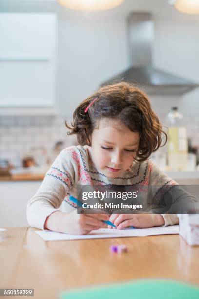 a girl sitting at a kitchen table writing a card or letter. - christmas colouring stock pictures, royalty-free photos & images