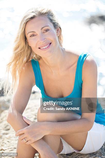smiling blond woman sitting on the rock - alleen één oudere vrouw stockfoto's en -beelden