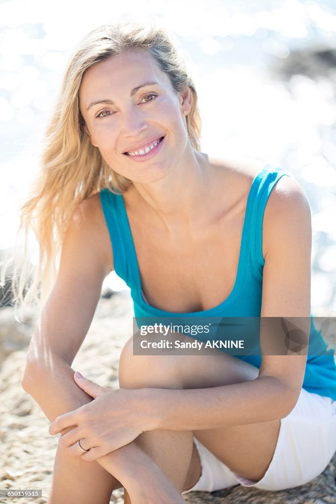 Smiling blond woman sitting on the rock