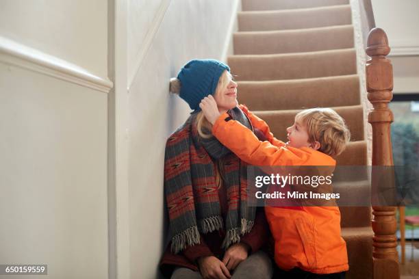 a boy pulling a hat over his mothers eyes. - adult laughing christmas stock pictures, royalty-free photos & images