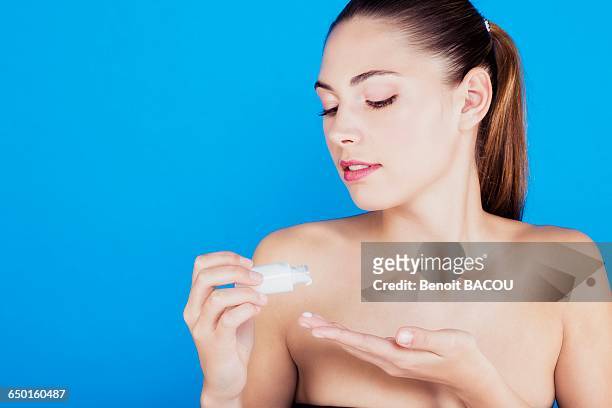 portrait of a young woman applying lotion on her skin - curvy white girl photos et images de collection