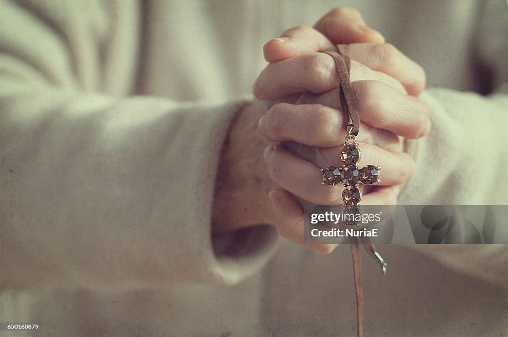 Senior woman with hands clasped holding a crucifix