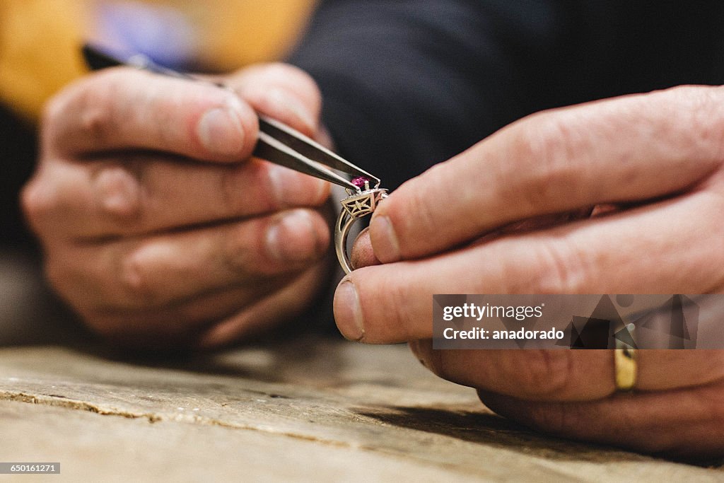 Close-up of a jeweler mounting a gemstone onto a ring