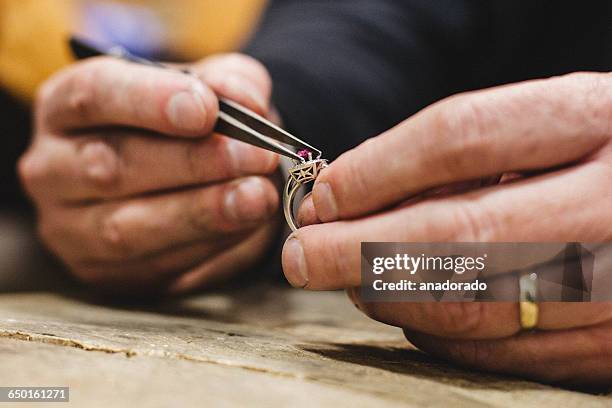 close-up of a jeweler mounting a gemstone onto a ring - juwelier stockfoto's en -beelden