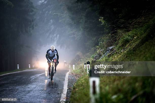 man cycling on a wet road in rain, salzburg, austria - racing bicycle stock pictures, royalty-free photos & images