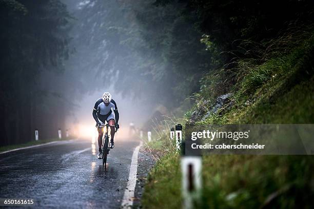 man cycling on a wet road in rain, salzburg, austria - bicicleta de corrida imagens e fotografias de stock