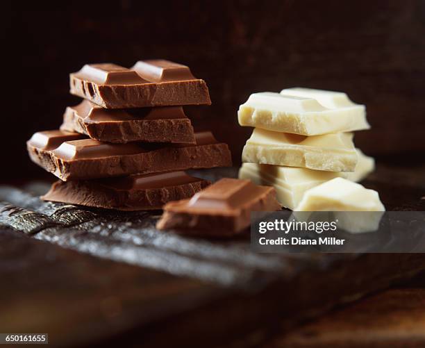 stacks of milk and white chocolate on wooden cutting board - weiße schokolade stock-fotos und bilder