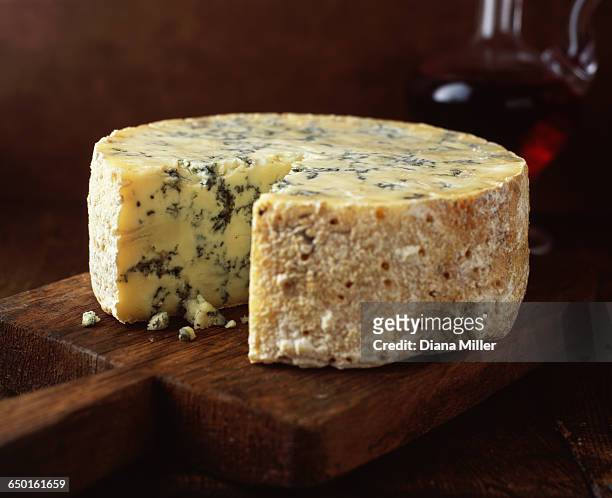 blue cheese round on wooden cutting board - portwein stock-fotos und bilder