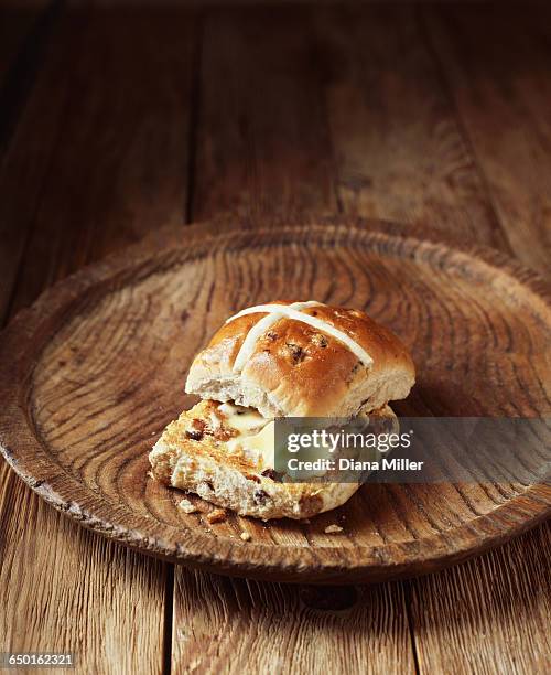 buttered hot cross bun on vintage wooden plate - hot cross bun stock pictures, royalty-free photos & images