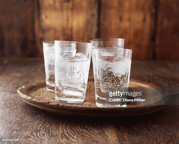 sparkling water in drinking glass with ice on vintage wooden plate - fizz photos et images de collection