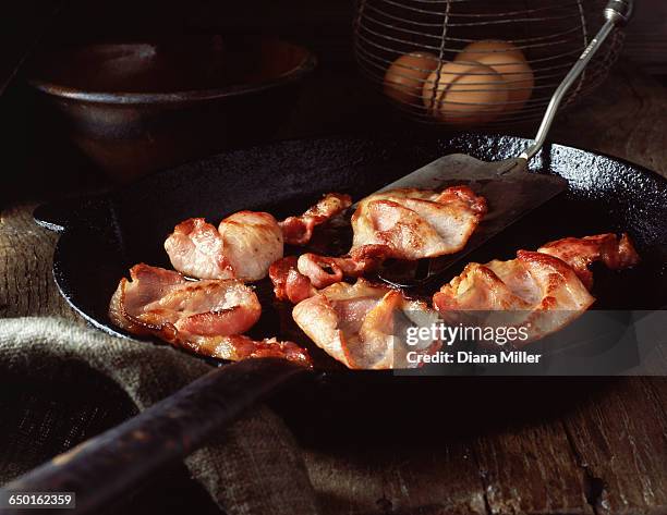 bacon rashers in vintage frying pan and eggs in wire basket - fried stock pictures, royalty-free photos & images