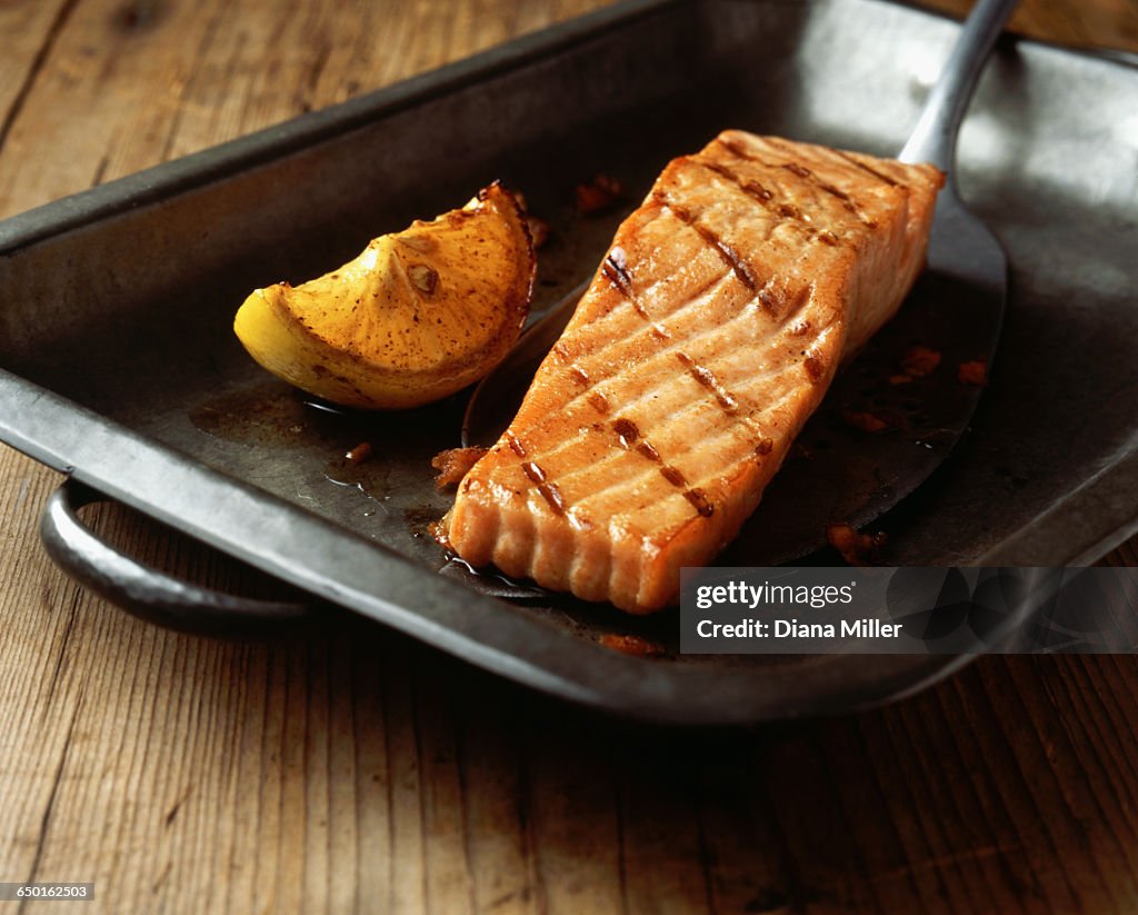 Grilled salmon with lemon wedge in baking tin
