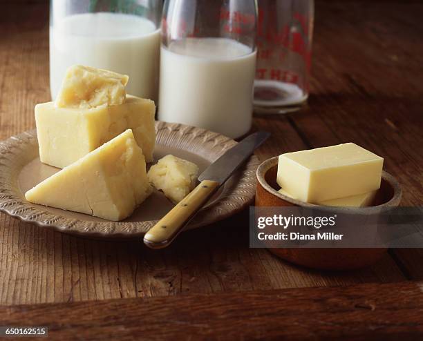 cheese, butter and milk bottles on wooden table - cheddar queso fotografías e imágenes de stock