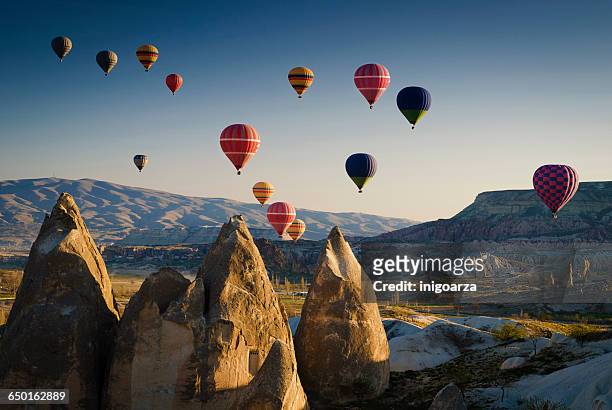 hot air balloons at sunrise flying over cappadocia, goreme, turkey - cappadocia hot air balloon stock pictures, royalty-free photos & images