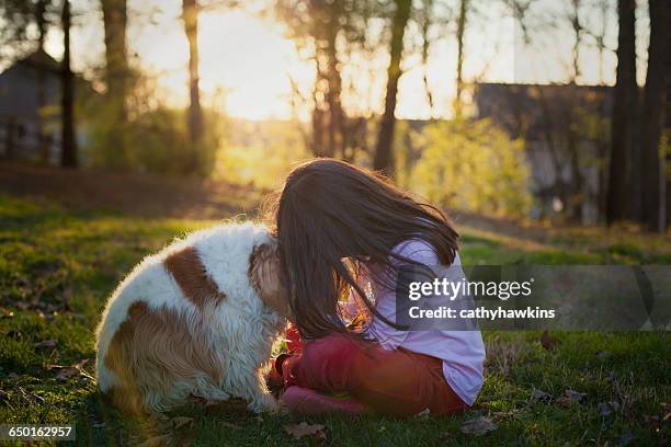 girl sitting and nuzzling with dog in garden - nuzzling stockfoto's en -beelden