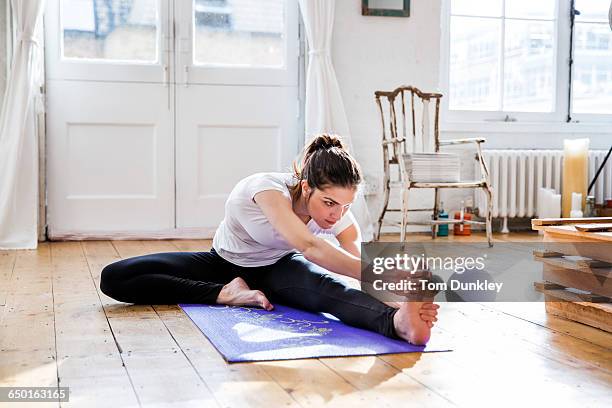 young woman practicing yoga, touching toes in apartment - zehenspitzen berühren stock-fotos und bilder