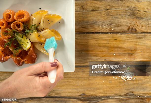 woman's hand glazing slices of salmon and starry sturgeon fish, ukraine - estilismo culinário imagens e fotografias de stock