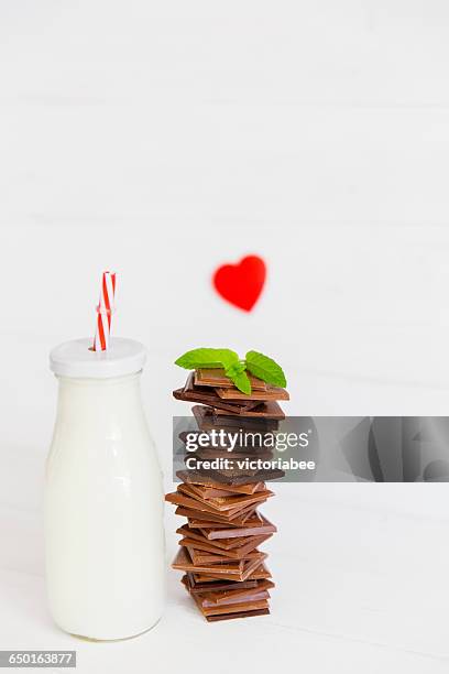 bottle of milk with stack of chocolate and heart shape - chocolate milk bottle stock pictures, royalty-free photos & images