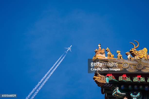 airplane flying over ancient building eave - modern tradition stock pictures, royalty-free photos & images