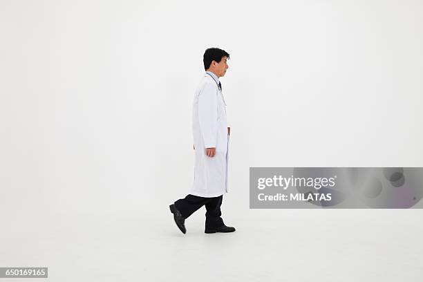 japanese man of white coat walking - doctors walking stock-fotos und bilder