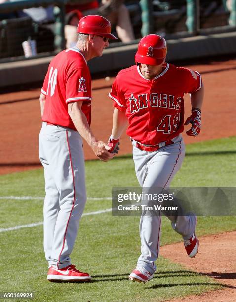 Ron Roenicke of the Los Angeles Angels greets Nolan Fontana after a home run against the Cincinnati Reds during the spring training game at Goodyear...