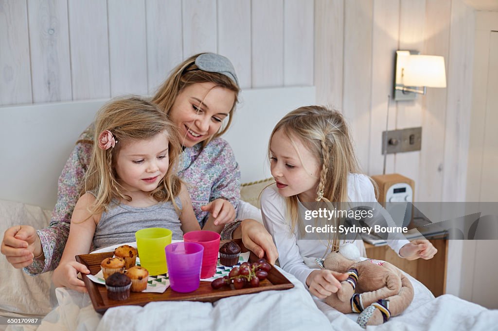 Mother and daughters having breakfast in bed