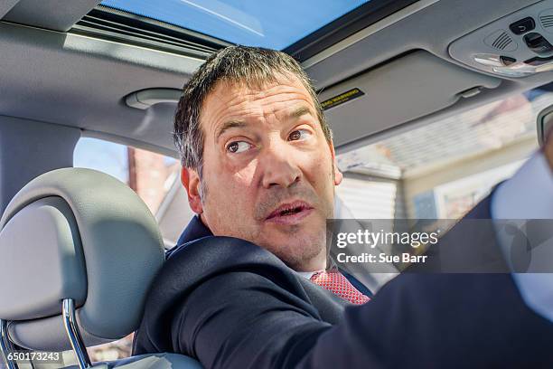 business man in car looking over shoulder - reverse stock-fotos und bilder