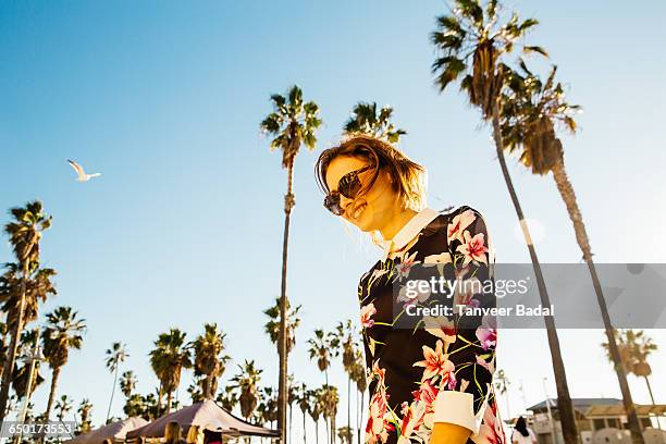 young woman walking outside, near palm trees, low angle view - venice california fotografías e imágenes de stock