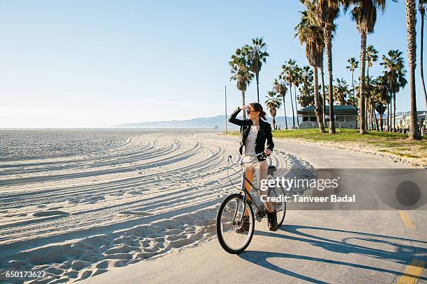 young woman cycling at beach looking out to sea, venice beach, california, usa - ロサンゼルス市 ストックフォトと画像